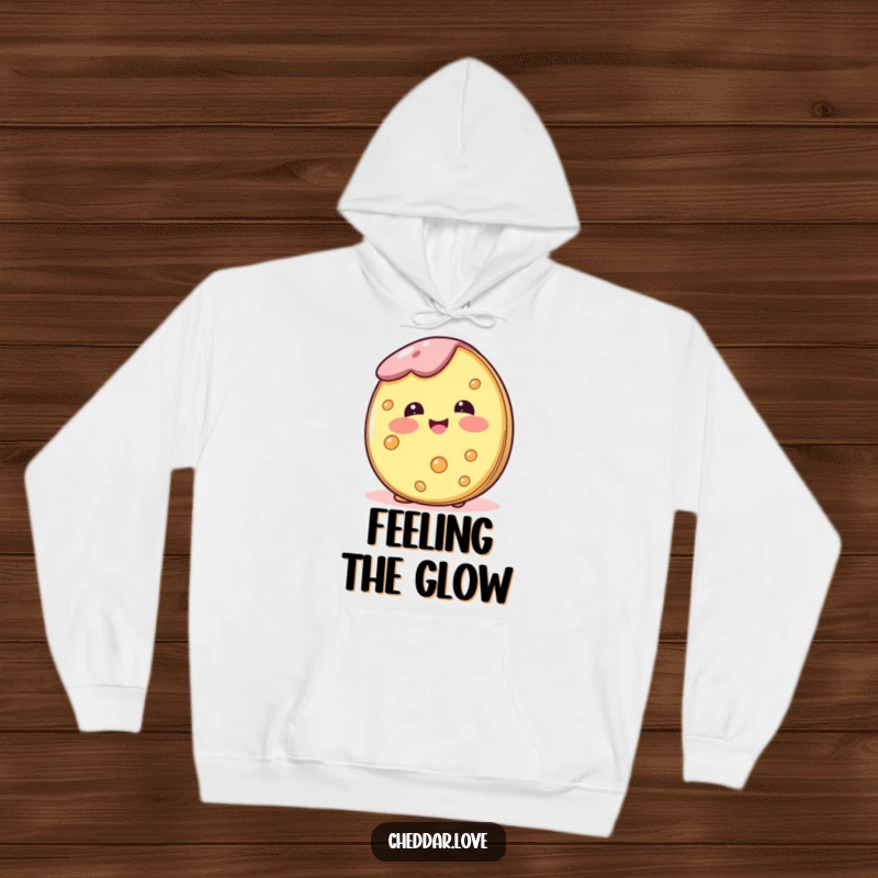 Funny, cozy hoodie featuring a cheese wheel blushing happily, perfect for staying warm and radiating positivity.
